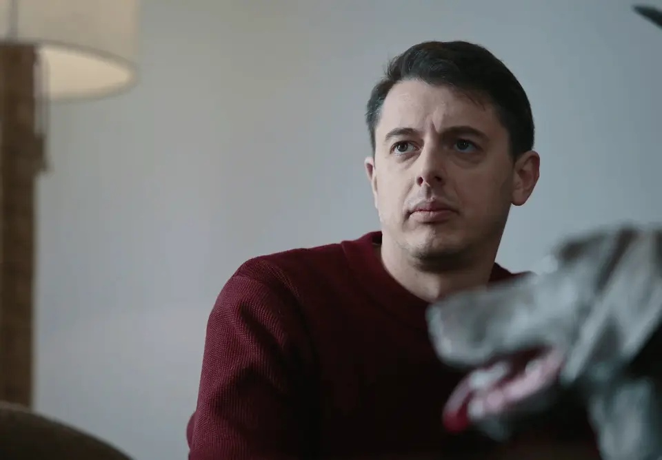 A man in a red sweater looking toward an unseen host