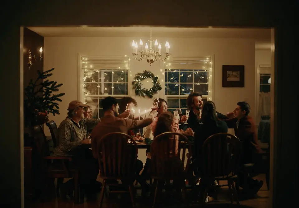 Friends raising their glasses around a warmly lit Christmas dinner table